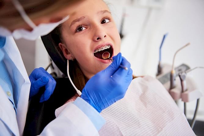 Dentist examining braces of child.