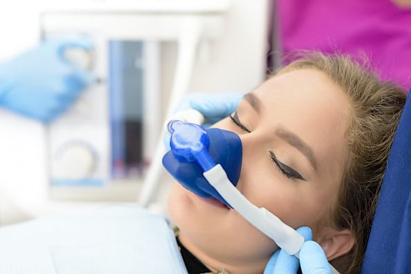 Woman on inhalation sedation during dental implant procedure.