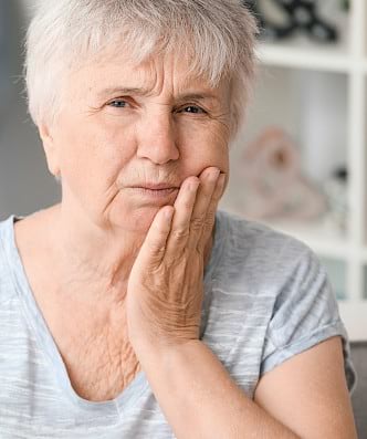 Old woman with mild pain after dental implant procedure.