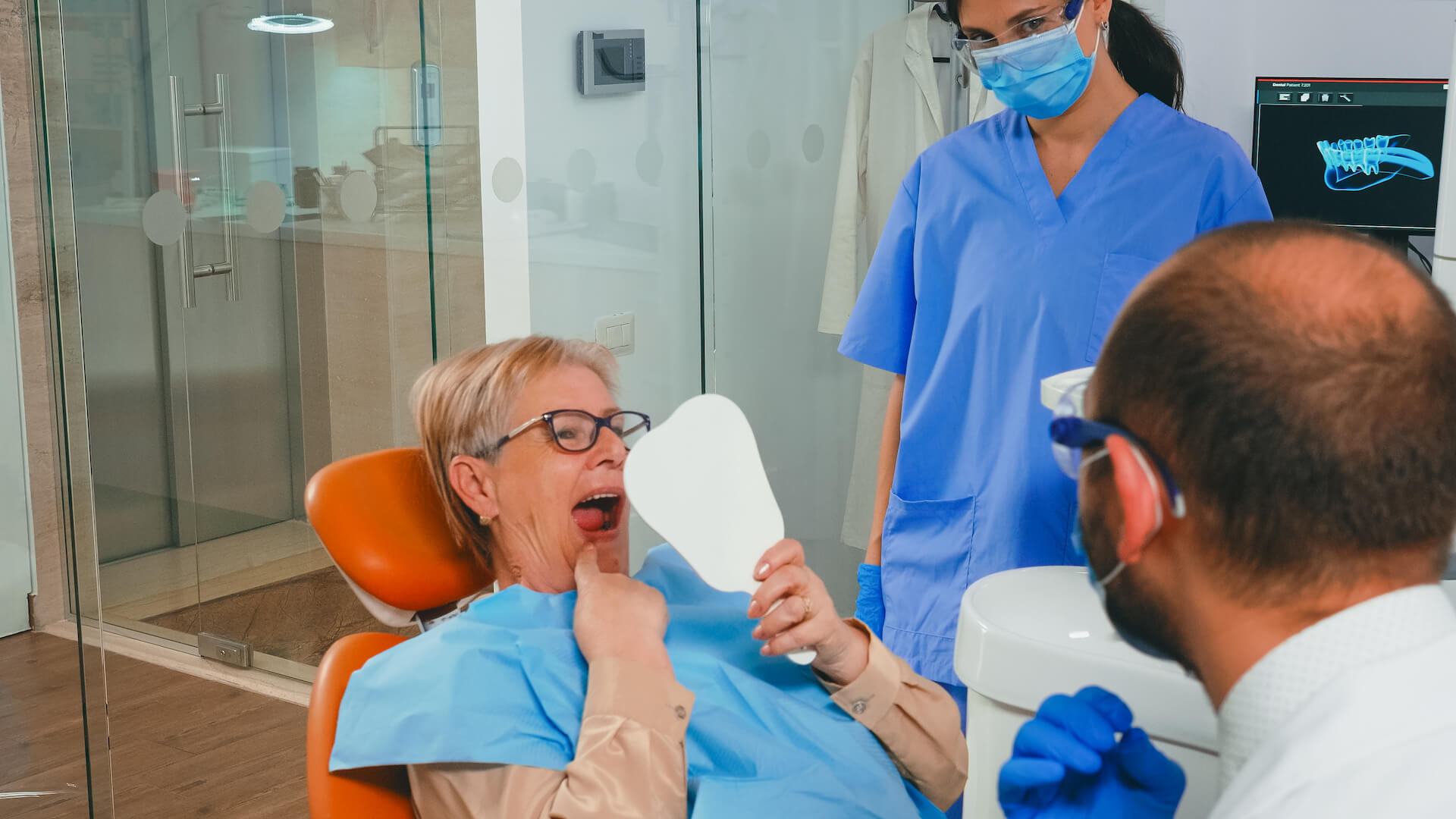 Woman checking teeth in the mirror after dental implant procedure.