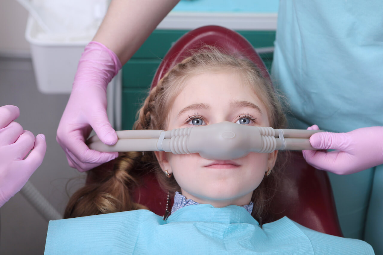Nitrous oxide gas being administered to a child through a mask for dental sedation.