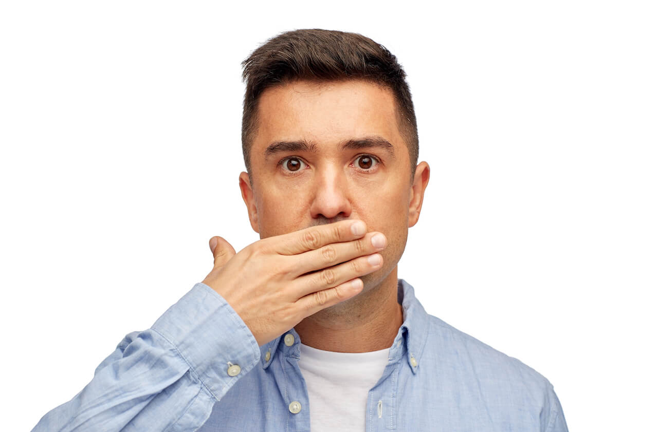 Man holding a hand over his mouth as if to hide his bad breath.