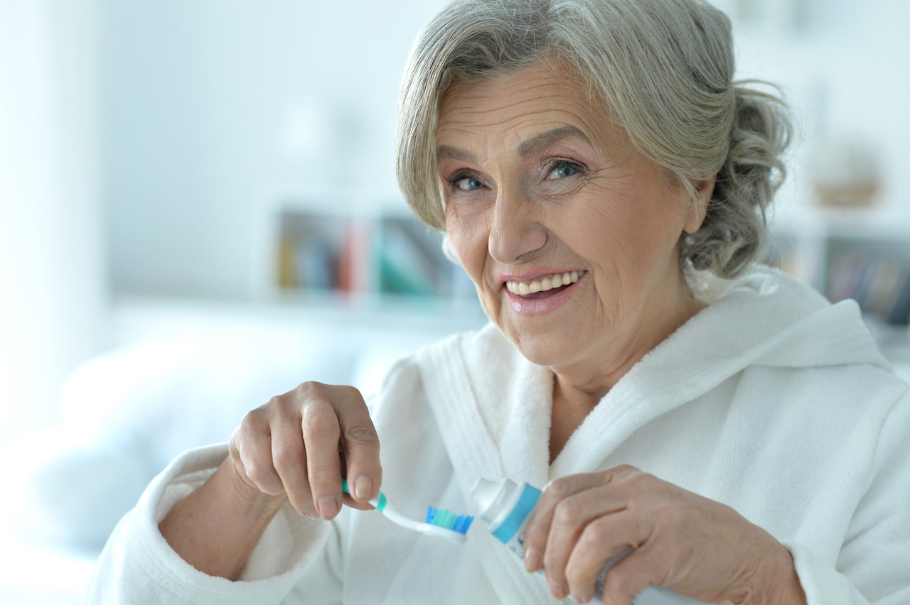 Old woman brushing teeth.